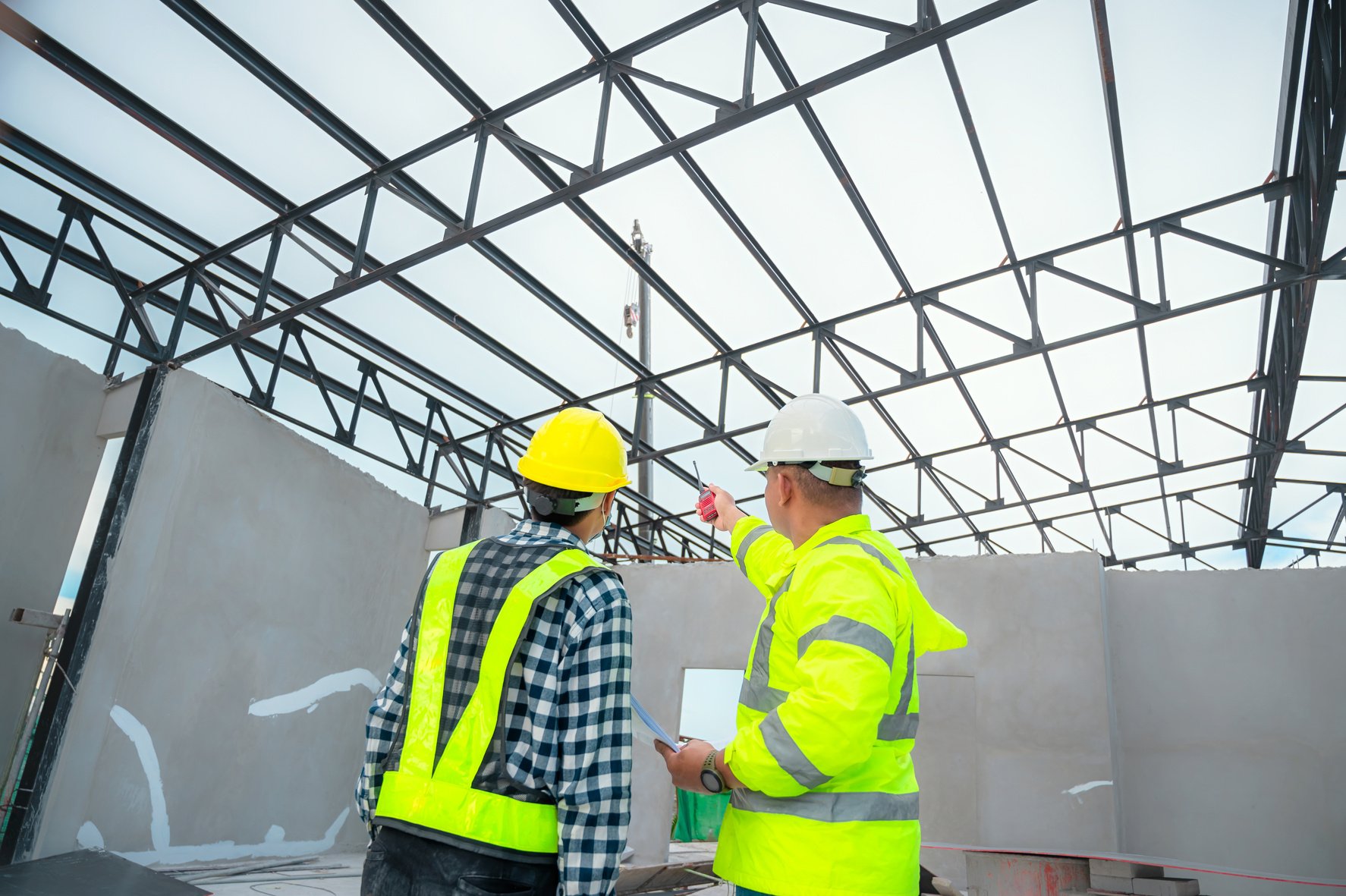 Civil engineer inspect structure at construction site against blueprint, Building inspectors jointly inspect the building structure with civil engineer. Civil engineer hold blueprint inspect building.