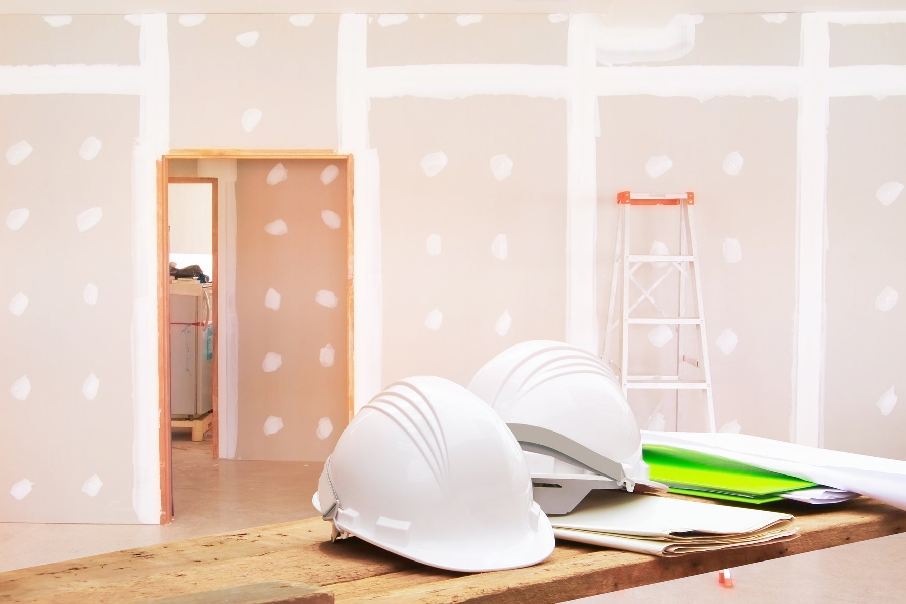 white safety helmet plastic white paper blueprint on Wooden floor in room work gypsum board wall interior decoration of home construction site